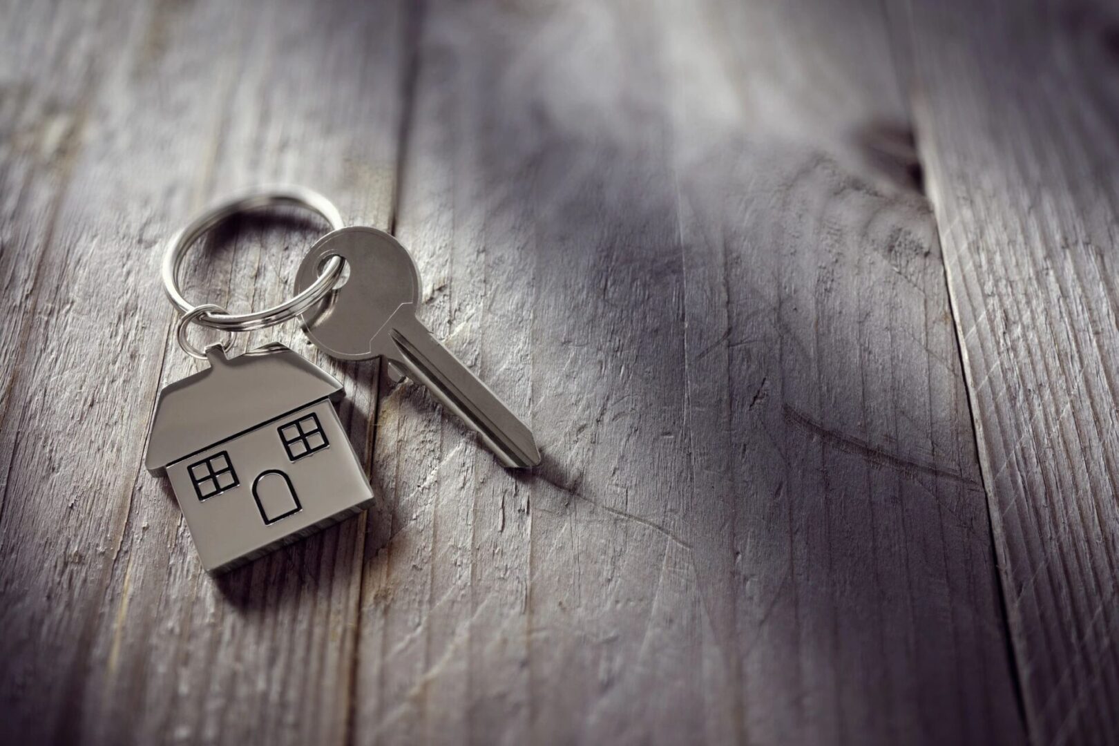 House keychain and key on wooden table